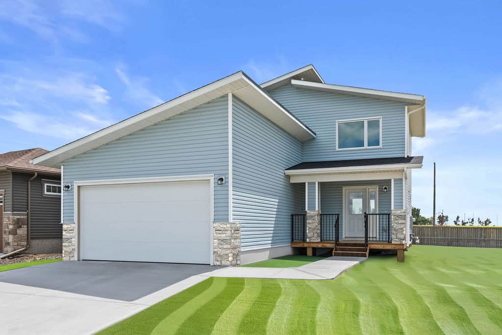 Modern blue suburban home with attached garage and landscaped yard for sale.